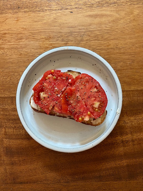 open face tomato and mayo sandwich on wood table.
